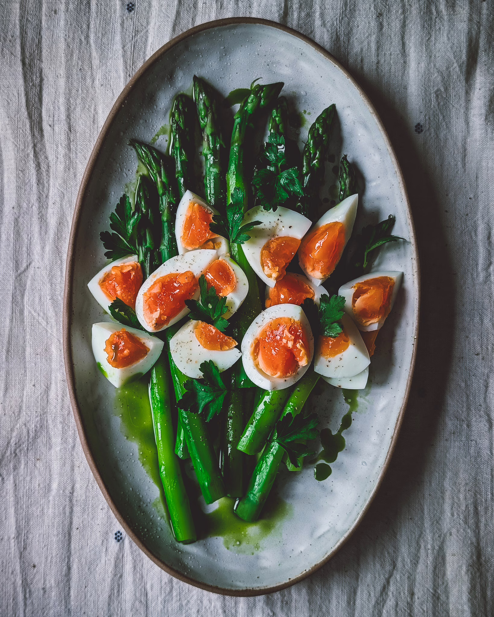 White ceramic serving plate with brown rim with asparagus and boiled eggs.