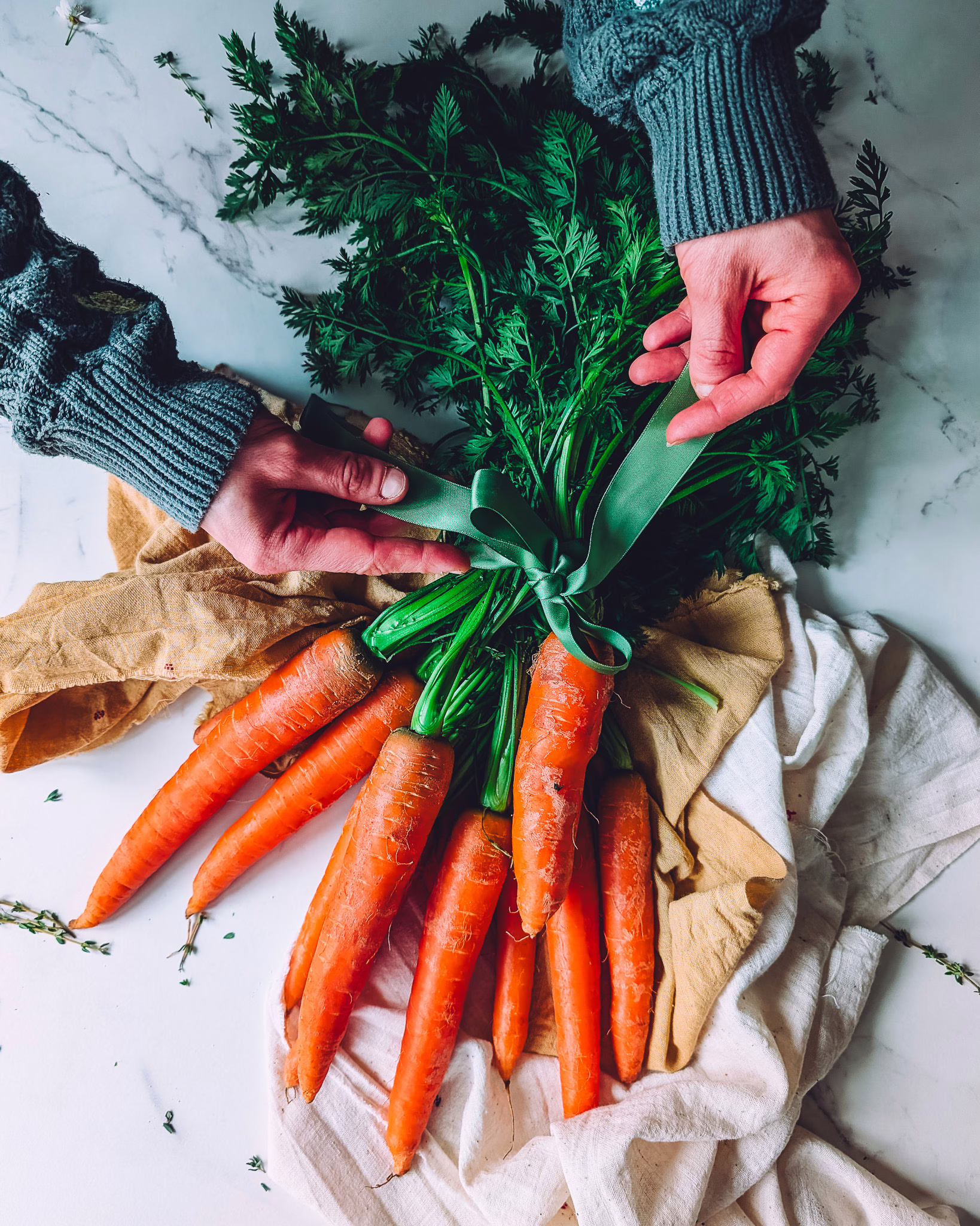 Person untying bunch of carrots held together with green ribbon