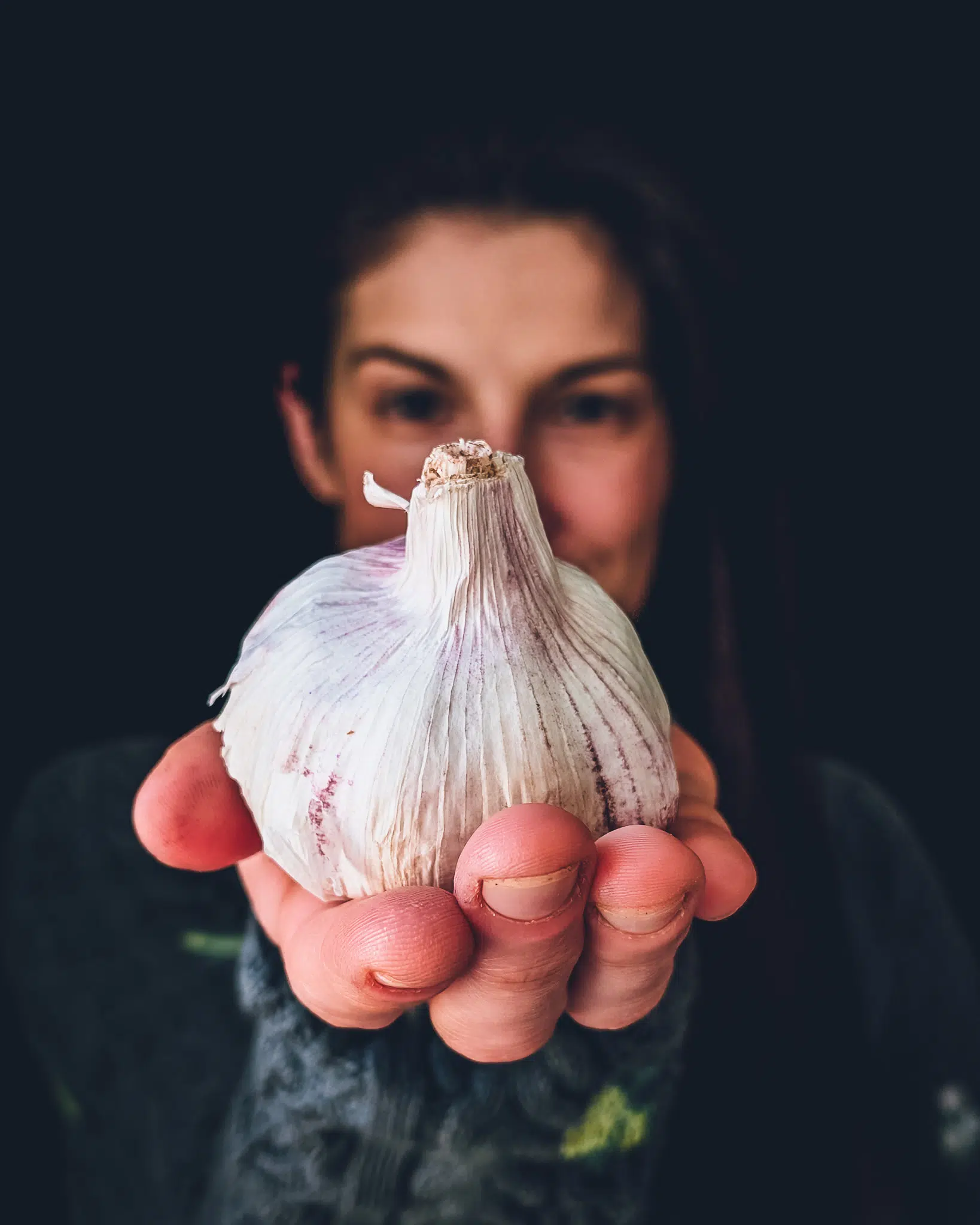 Woman holding bulb of garlic in front of her