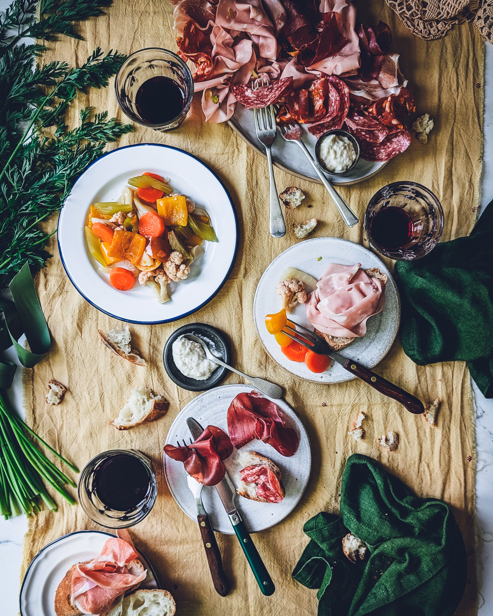 Giardiniera Italian pickled vegetables served with charcuterie, herbs, and wine in a flat lay composition