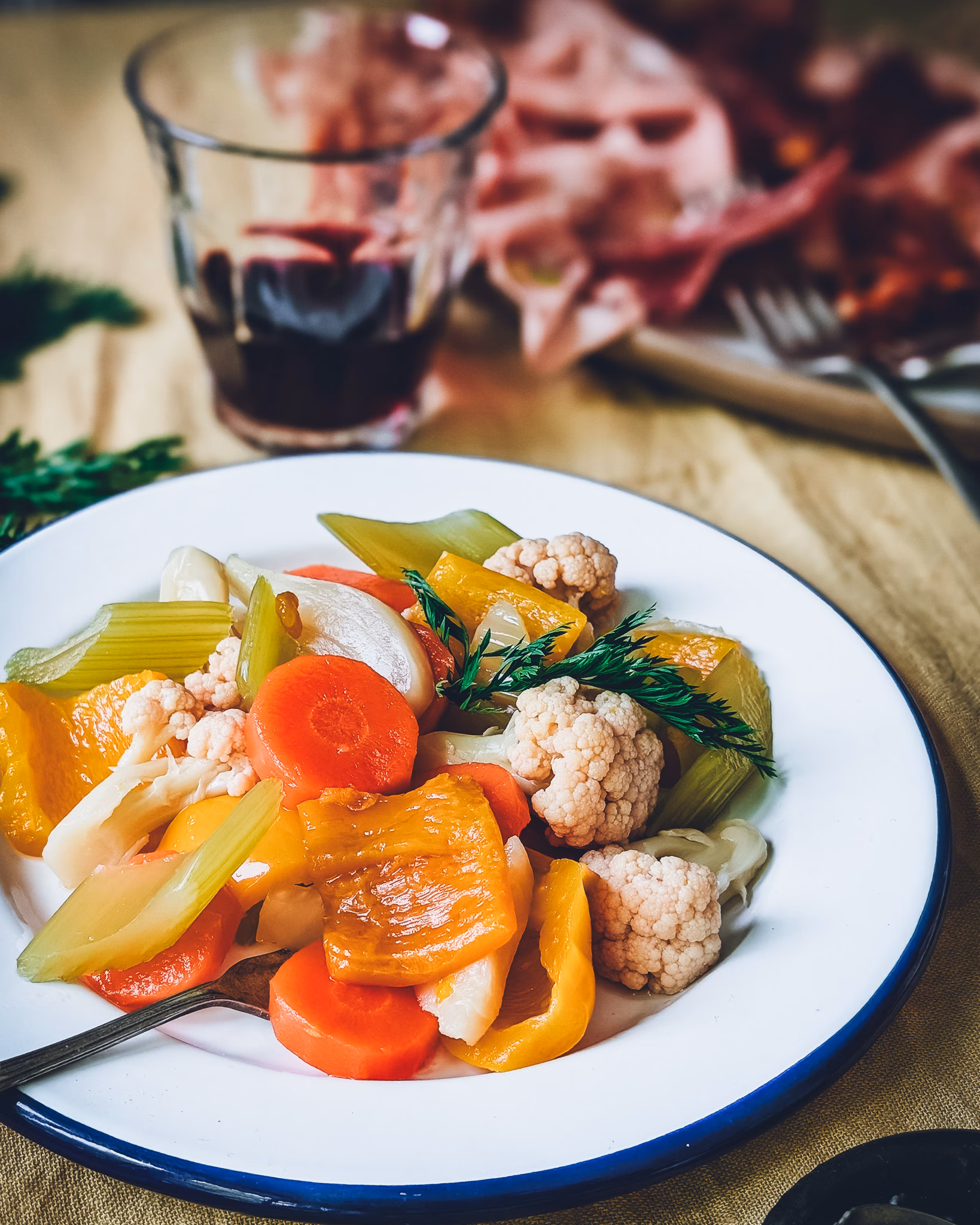 Giardiniera Italian pickled vegetables served with charcuterie, herbs, and wine in a flat lay composition