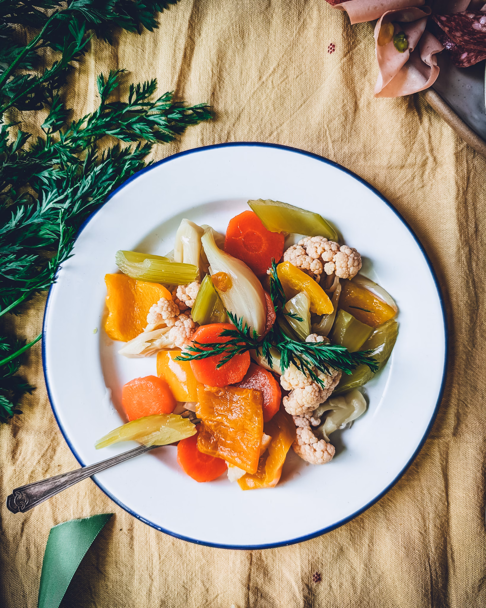 Giardiniera Italian pickled vegetables served with charcuterie, herbs, and wine in a flat lay composition