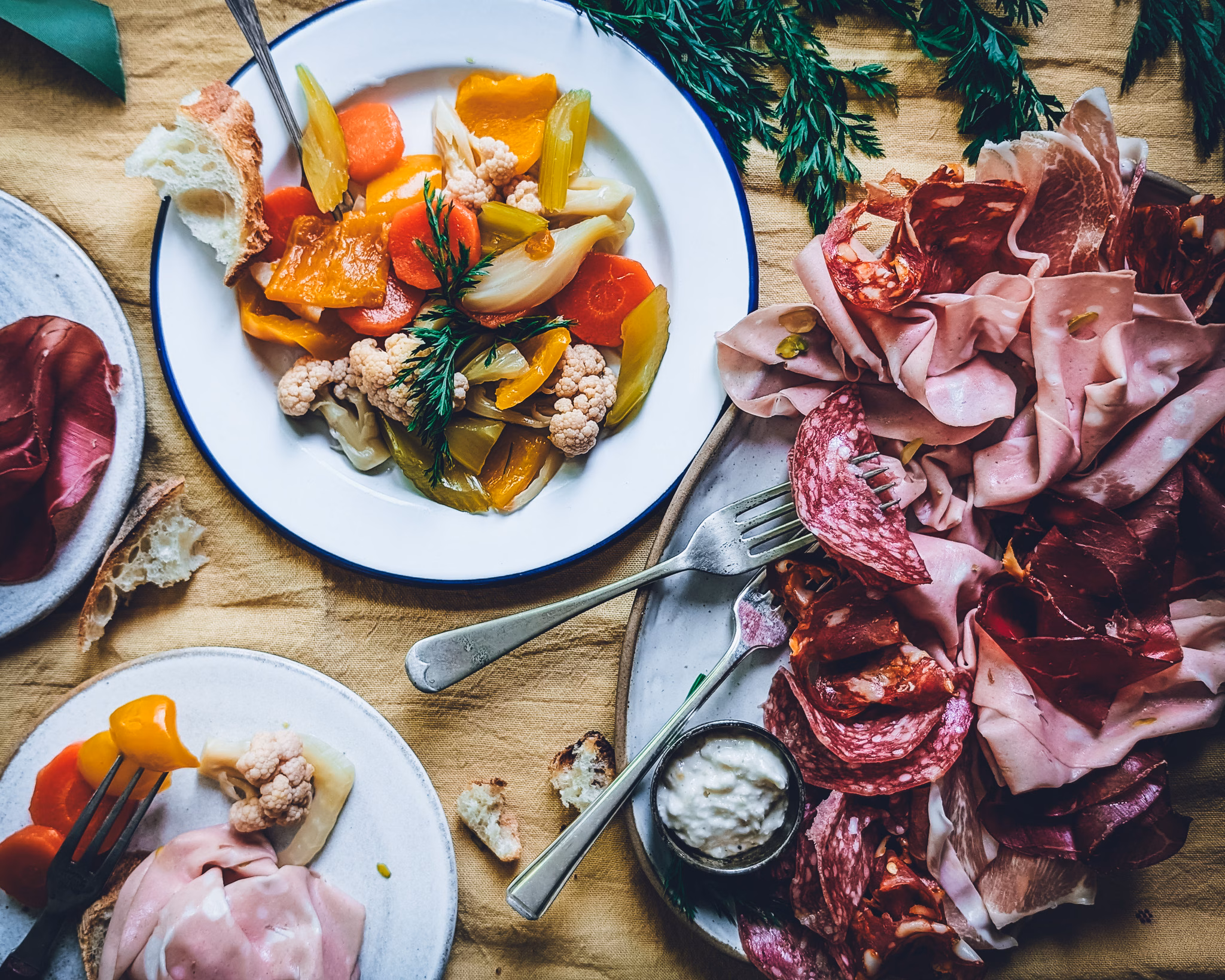 Giardiniera Italian pickled vegetables served with charcuterie, herbs, and wine in a flat lay composition