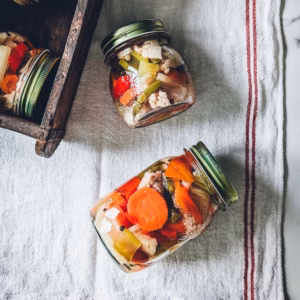 Two jars of vibrant giardiniera - Italian pickled vegetables on a striped tea towel