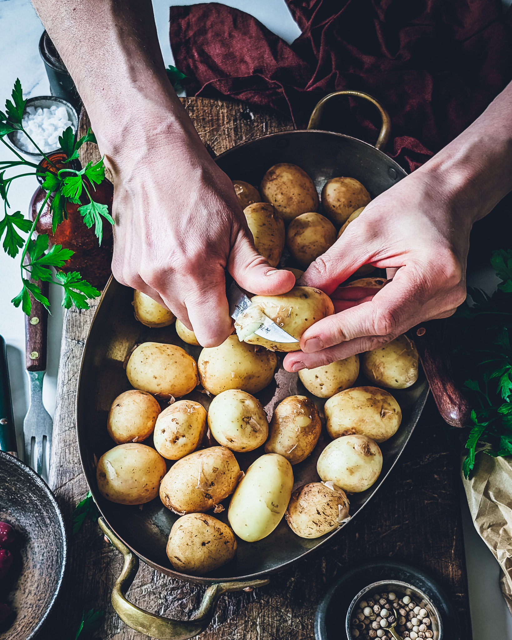 Hands peeling potatoes in a bowl.
