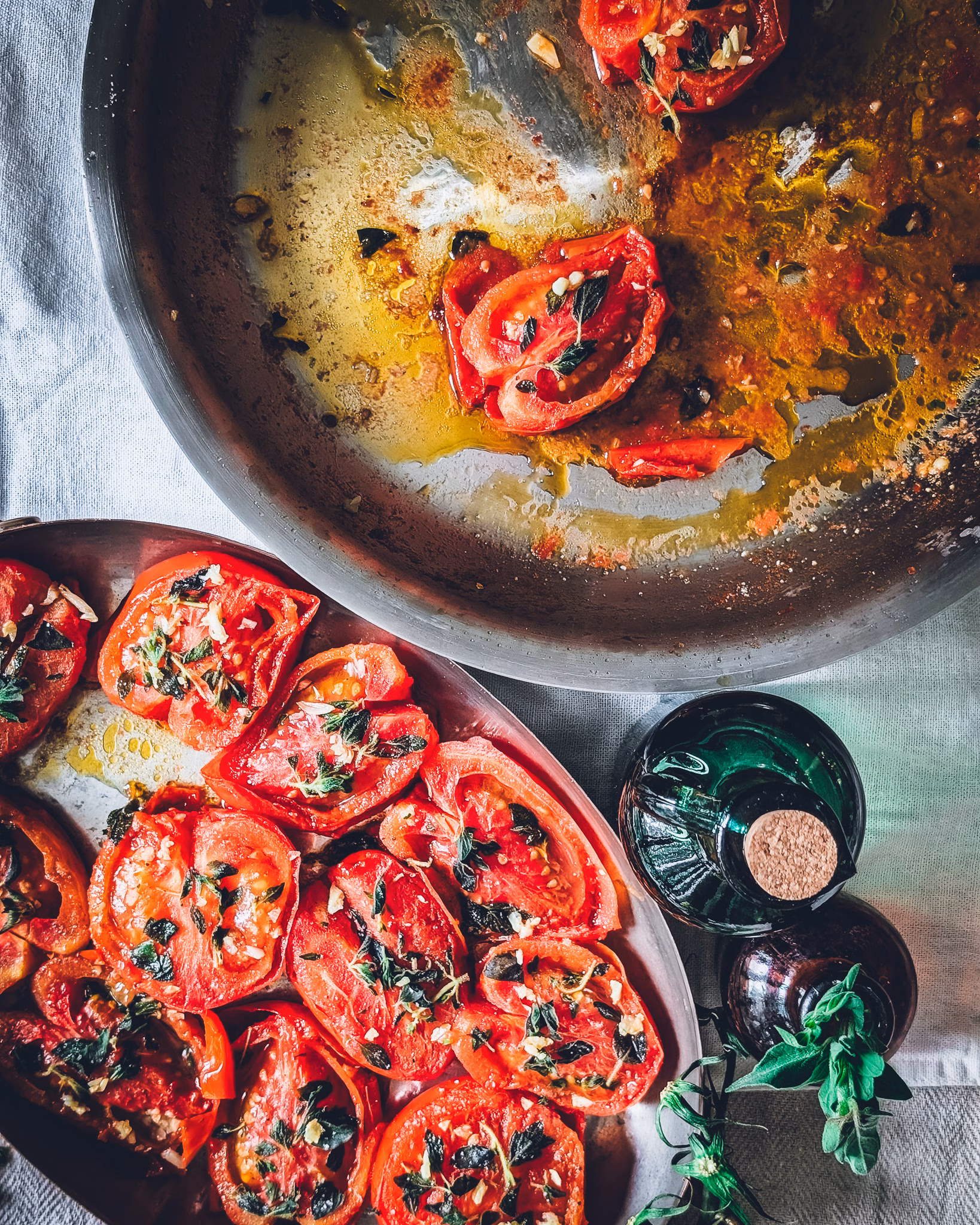 Pan of pan-fried tomatoes half empty. Next to the pan a serving plate full of tomatoes.