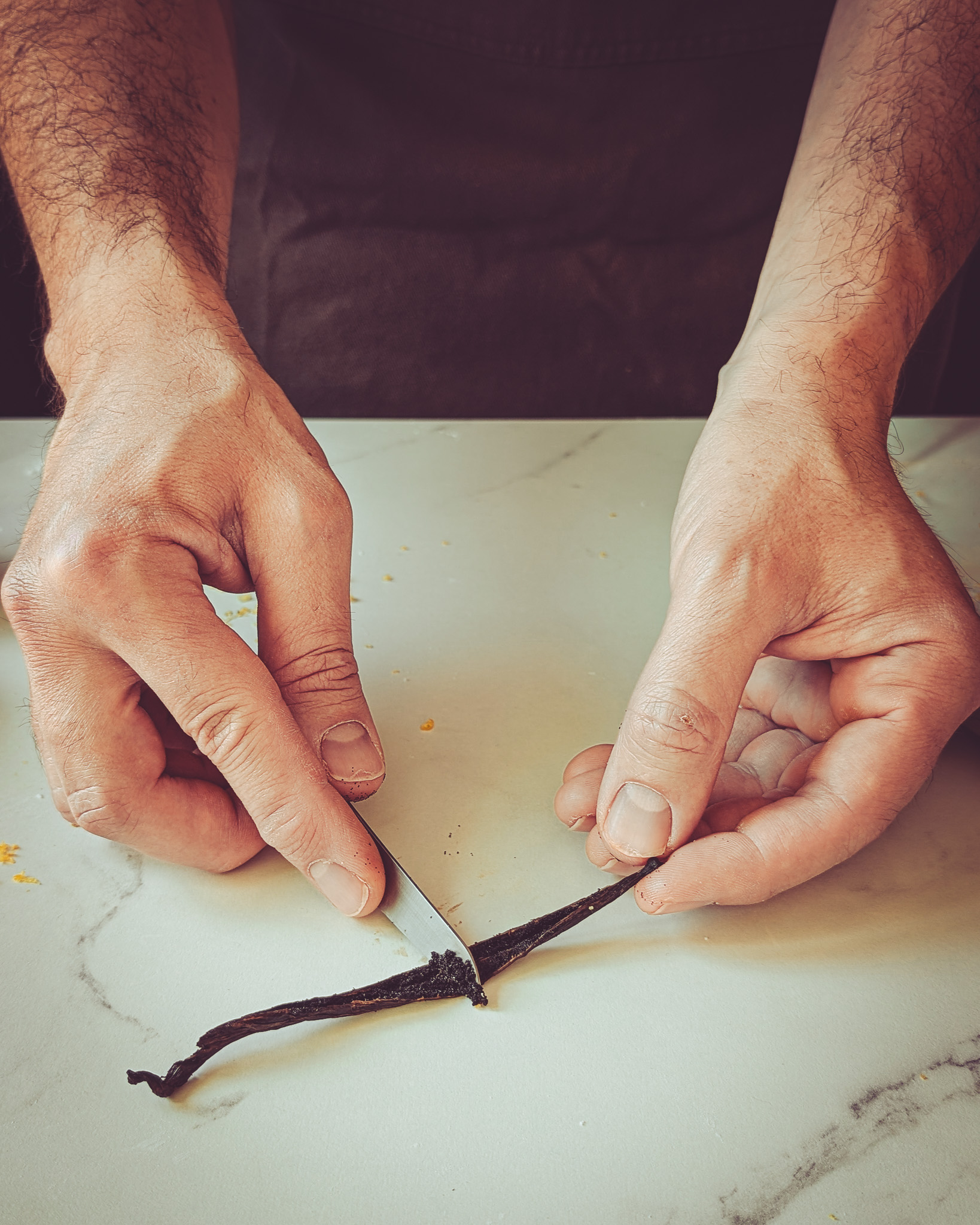 Hands of man scraping a vanilla pod
