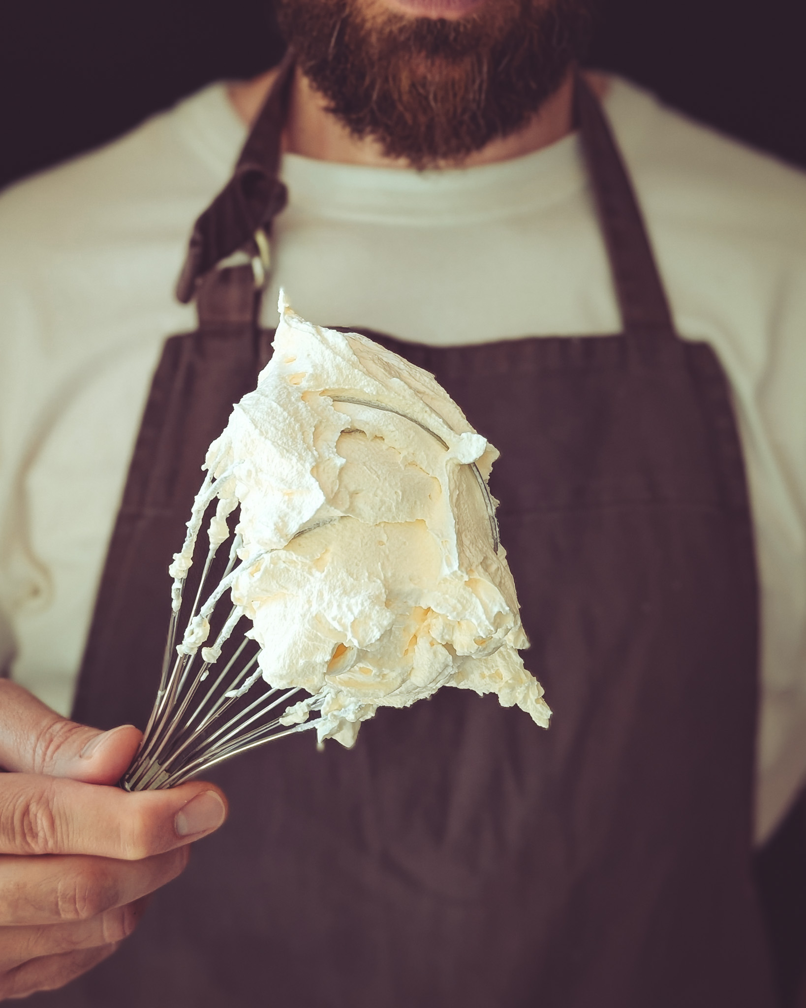 Man holding whisk with whipped cream