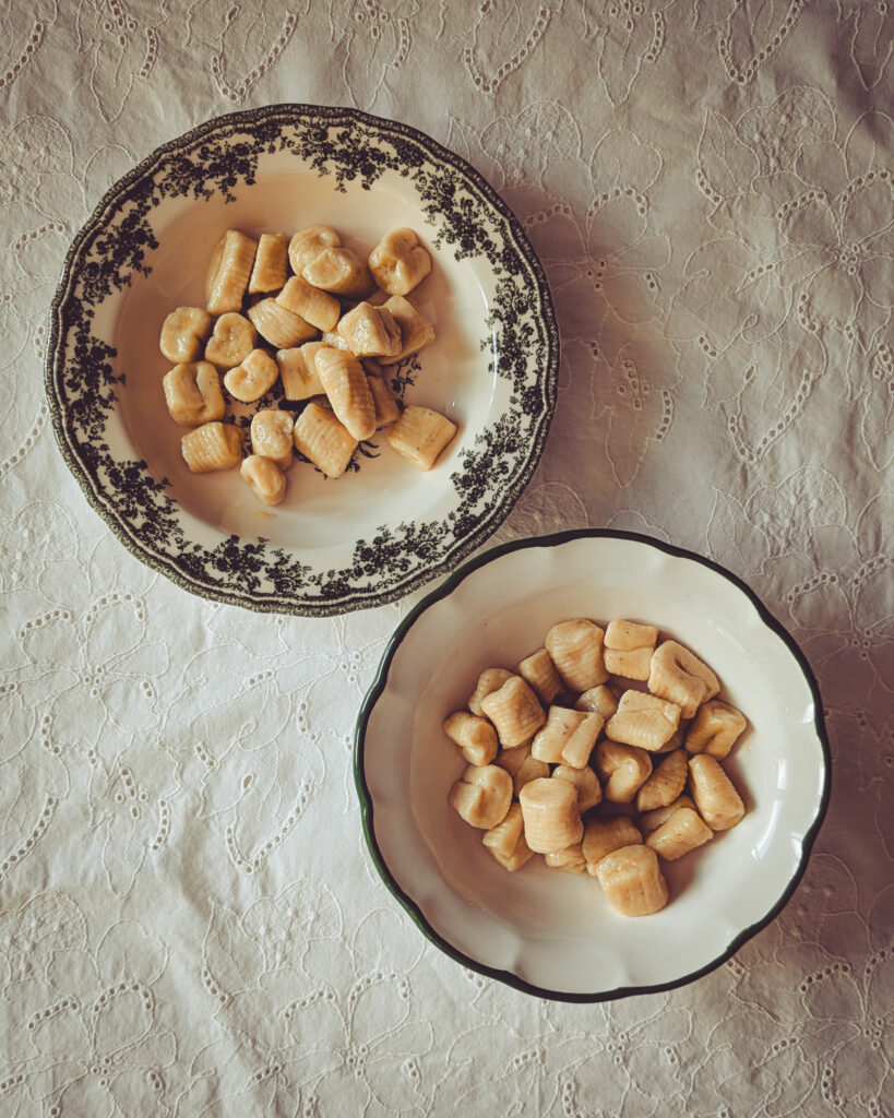 Two plates full of cooked gnocchi.