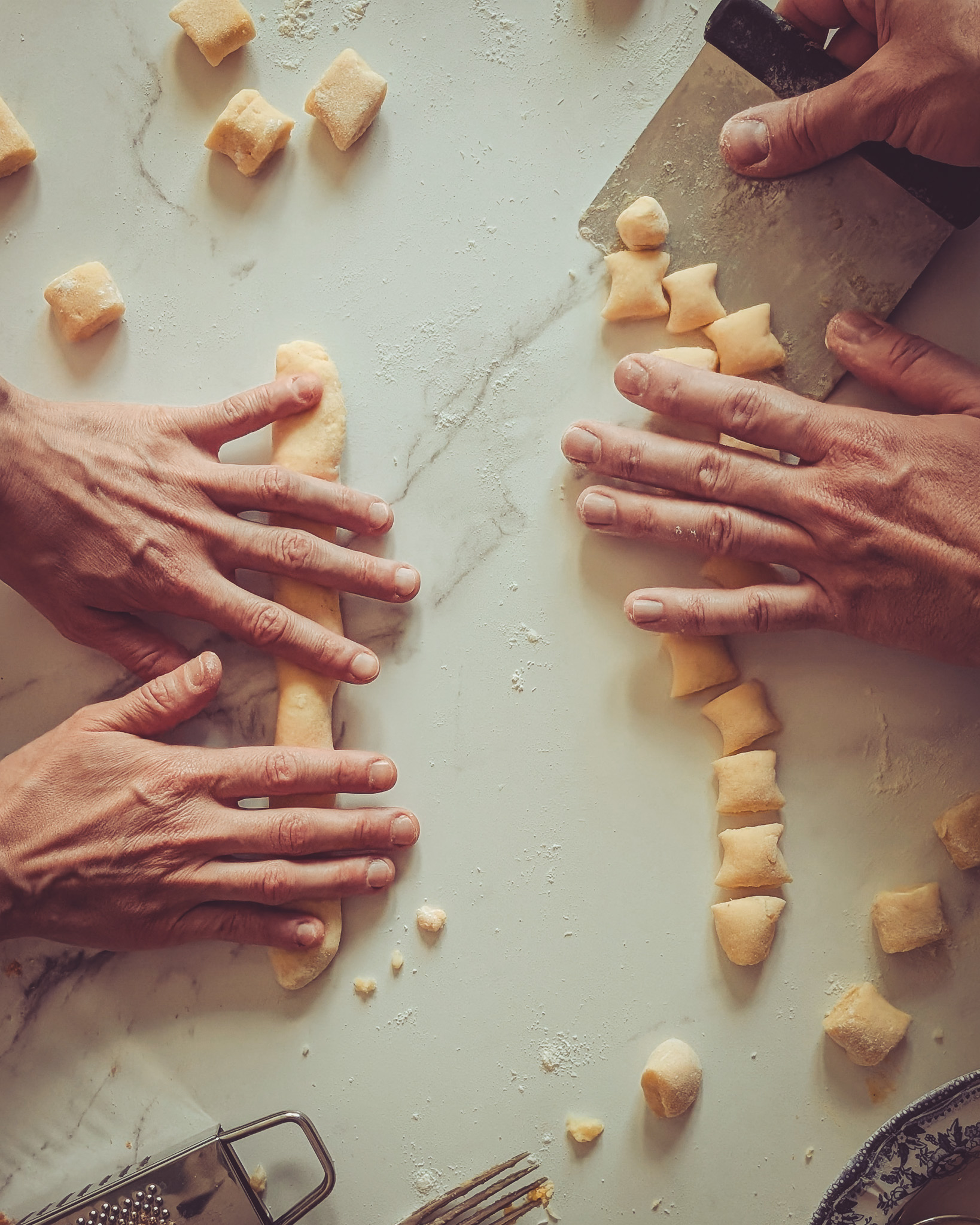 Hands of two people rolling and making gnocchi.