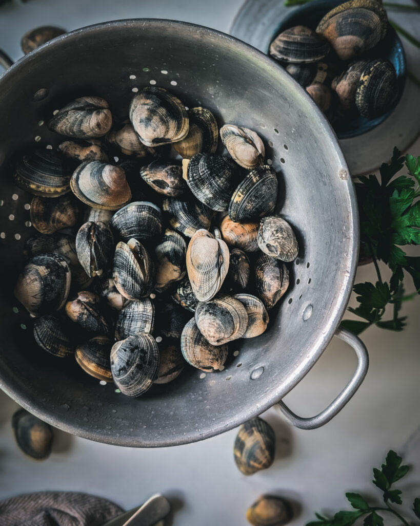 Colander full of vongole on a marble table.