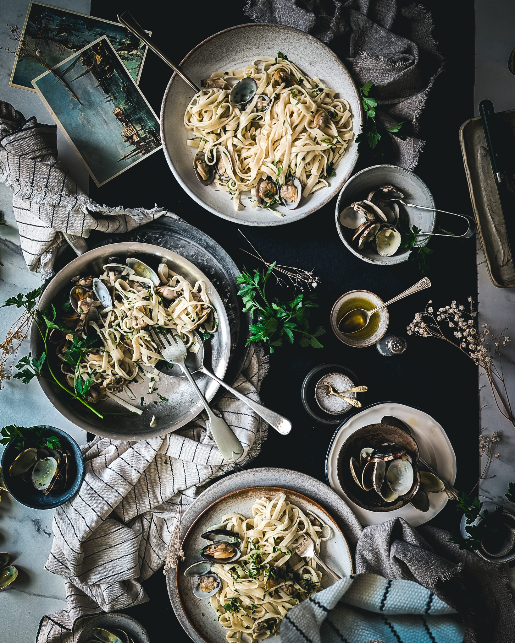 Table full of plates with linguine alle vongole and a pan half eaten.