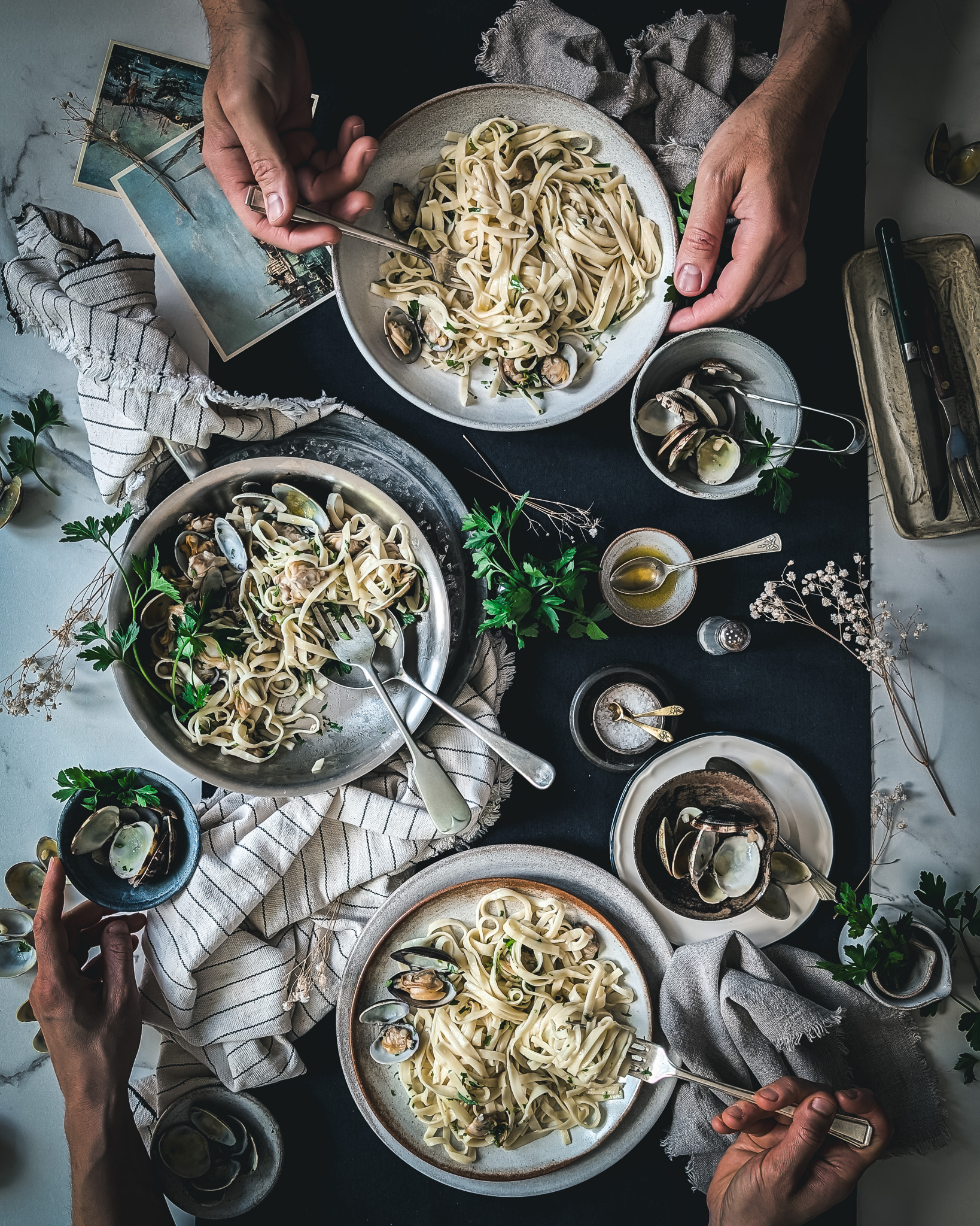 Two people sitting at a table and eating from plates full of linguine alle vongole.