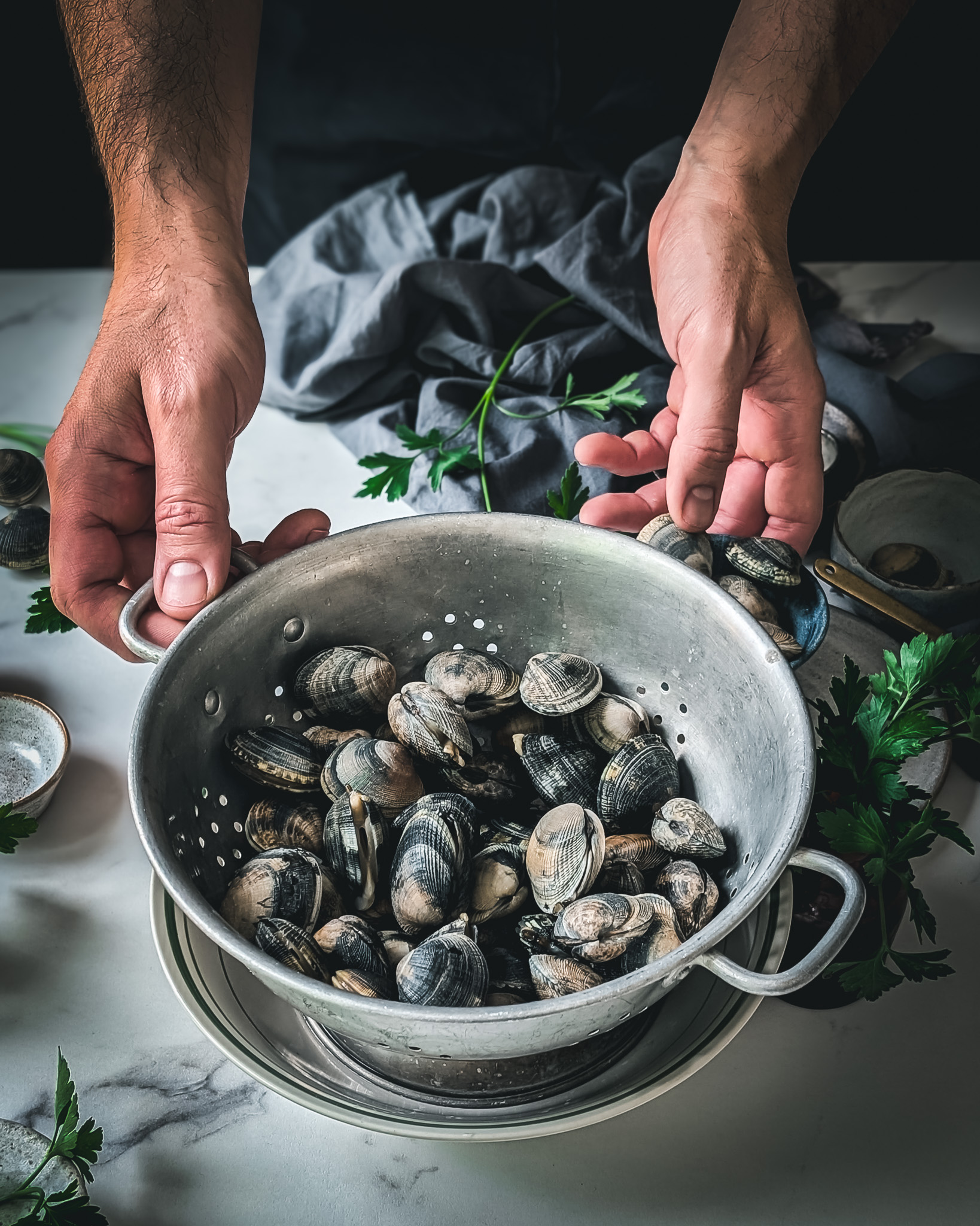 Person holding colander full of vongole.