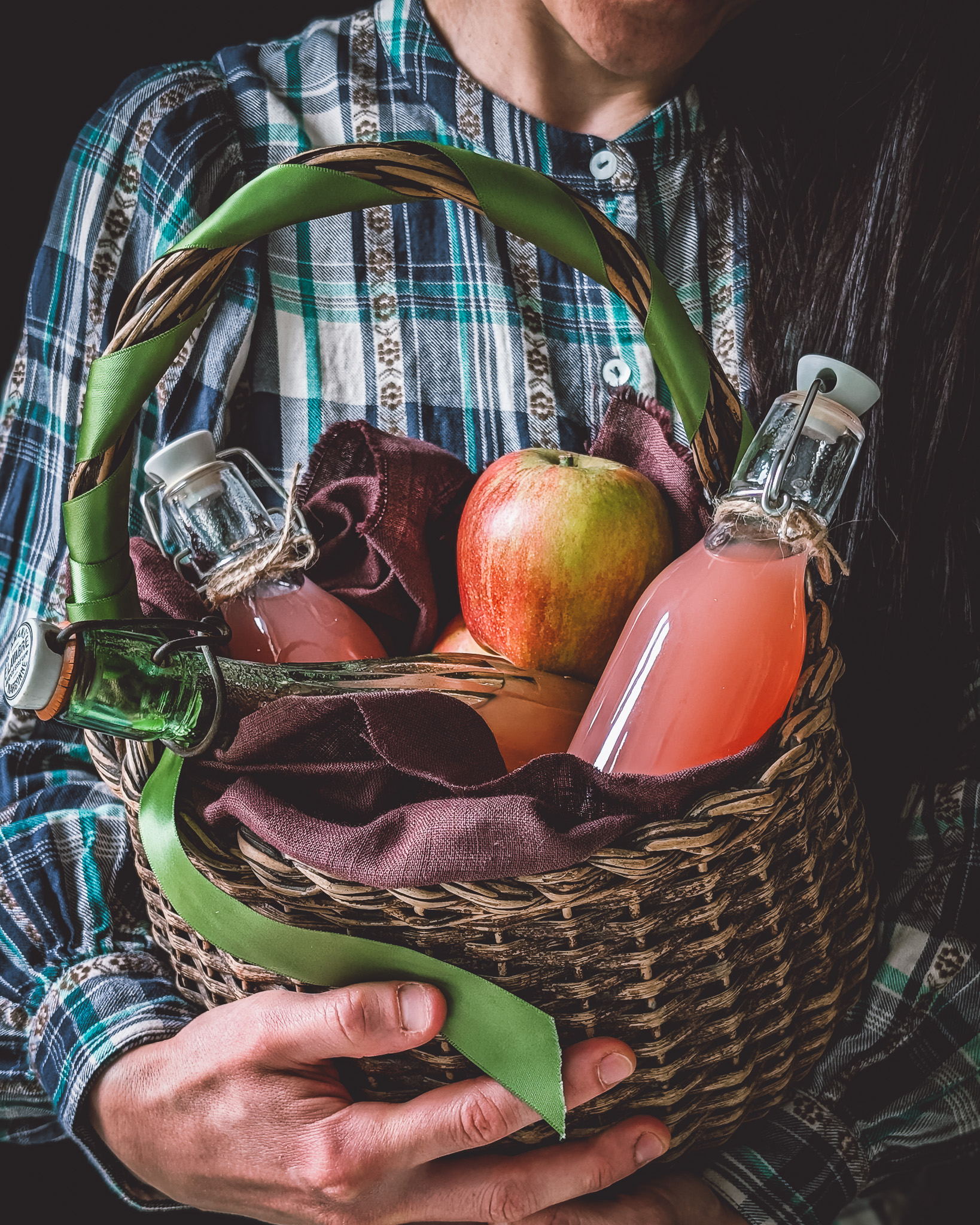 Woman holding basket full of apple juice bottles and apples