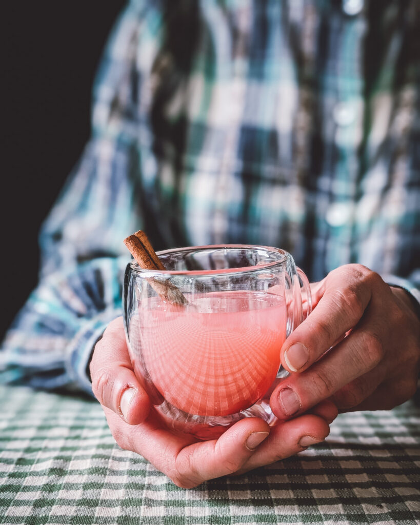 Person drinking apple juice from a transparent mug